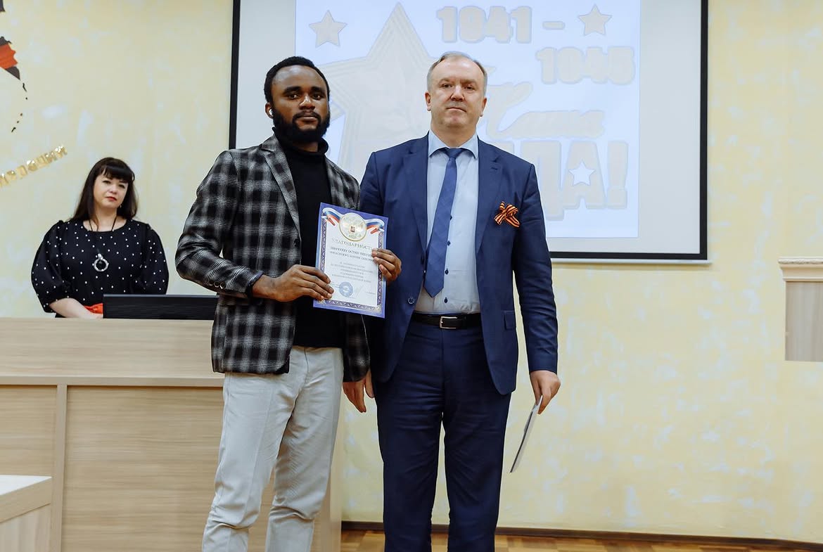 Austine receiving a university award certificate
